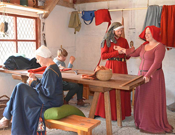 Vier Menschen in Mittelalterkleidung sind um einen Tisch versammelt